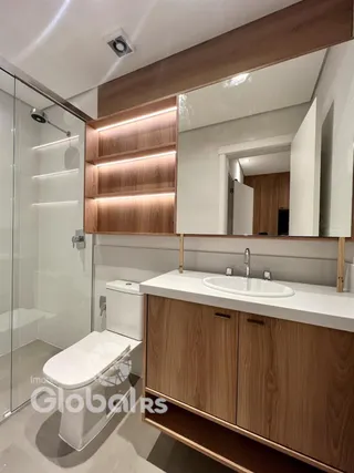 Banheiro moderno com bancada de madeira e box de vidro.
