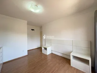 Sala de estar com piso de madeira e paredes brancas em um imóvel no Brasil.