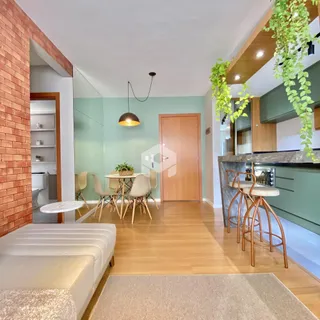 Sala de estar com piso de madeira e cozinha integrada em um ambiente claro.