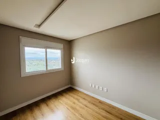 Quarto com piso de madeira e janela com vista para a paisagem.