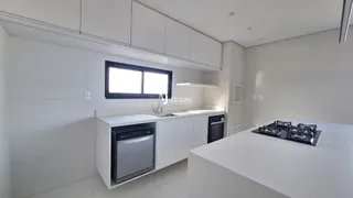 Vista da cozinha moderna com armários brancos e bancada clara.