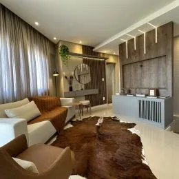 Sala de estar com painel de madeira e cortinas claras.