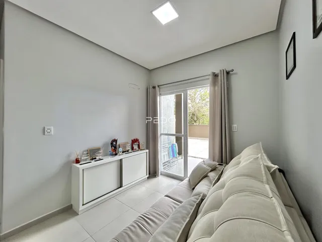 Sala de estar moderna com sofá e painel de TV em um ambiente claro.