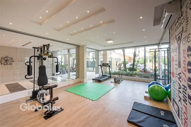 Sala ampla com piso de madeira e equipamentos de ginástica.