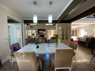Sala de jantar com mesa branca e cadeiras claras em um ambiente interno.