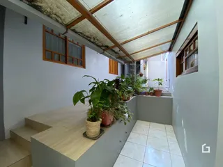 Vista interna de um ambiente com teto de madeira exposta e plantas decorativas.