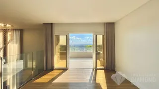 Sala de estar com piso de madeira e portas de vidro que dão para uma vista panorâmica.