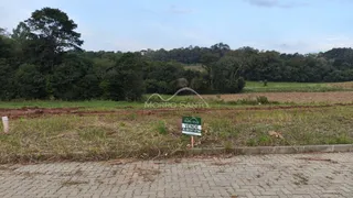 Vista de um campo aberto com vegetação densa ao fundo e uma placa de venda.
