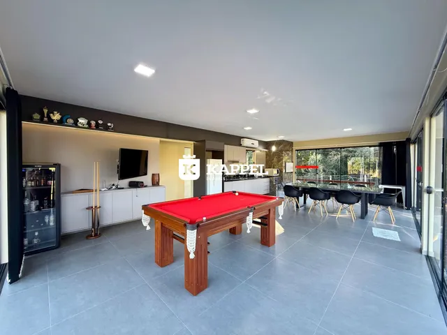 Sala ampla com mesa de bilhar e vista para o exterior.