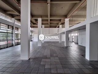 Foto de um espaço interno amplo com pilares brancos e piso de cerâmica.