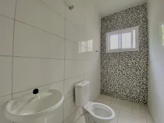 Banheiro com pia e vaso sanitário em revestimento branco.