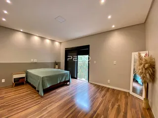 Quarto com cama e piso de madeira no interior da residência.