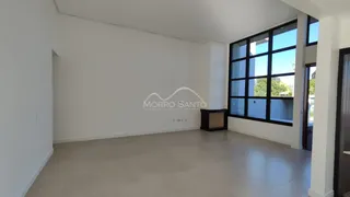 Foto de uma sala ampla e clara com piso de porcelanato e grandes janelas escuras.