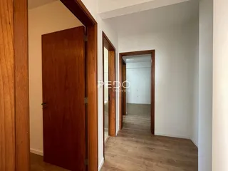 Vista de um corredor interno com portas de madeira em uma residência.