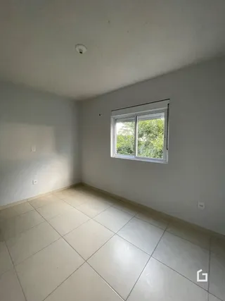 Uma foto de um cômodo interno com paredes brancas e piso de cerâmica.