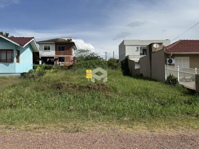 Vista externa de casas em Lajeado, Brasil, com vegetação alta na frente.