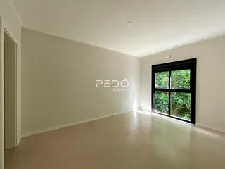 Ambiente interno de uma sala ampla com piso claro e grande janela.