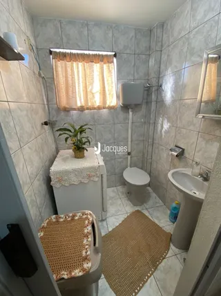 Foto de um banheiro com azulejos brancos e louças sanitárias.