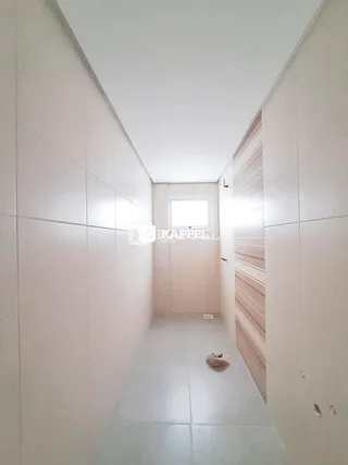 Corredor interno com paredes brancas e piso de cerâmica.