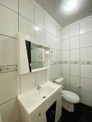 Um banheiro com paredes brancas e revestimento cerâmico.