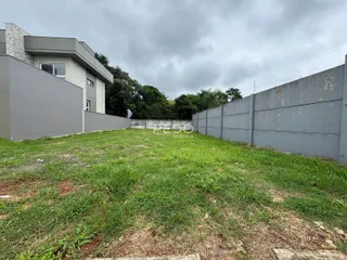 Vista da fachada de uma residência com jardim gramado e muro de vedação.