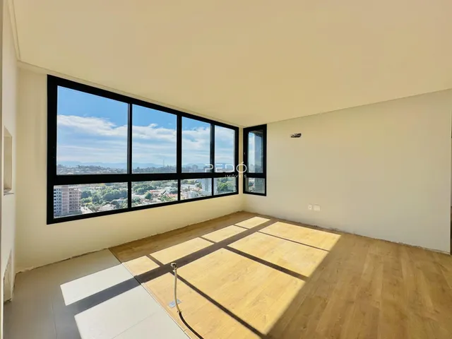 Sala ampla com grande janela oferecendo vista para a paisagem urbana.