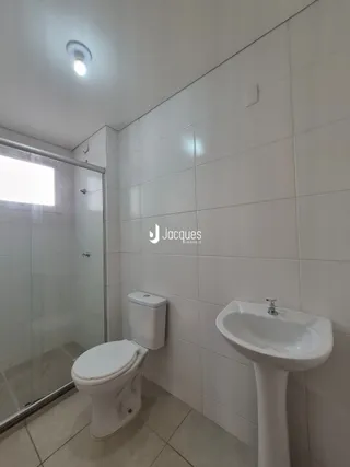Foto de um banheiro com azulejos brancos e louças sanitárias brancas.