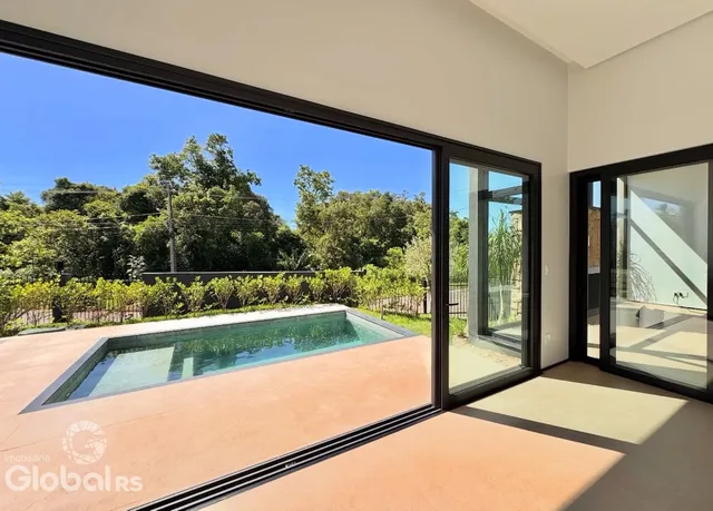 Vista externa de uma propriedade com piscina e vegetação ao fundo.