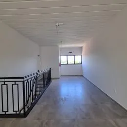 Corredor interno com piso claro e guarda-corpo preto.
