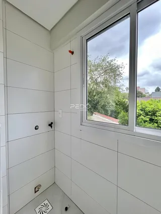 Vista de um corredor interno com paredes brancas e uma grande janela.