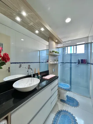 Banheiro moderno com bancada escura e box de vidro.