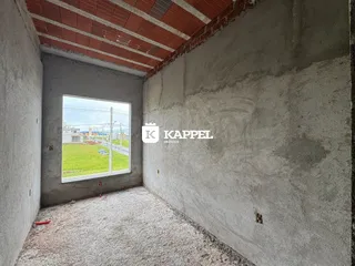 Foto de um cômodo interno com paredes de concreto aparente e uma janela para um gramado.