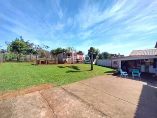 Um gramado grande e uma cerca de madeira são visíveis no quintal da propriedade.