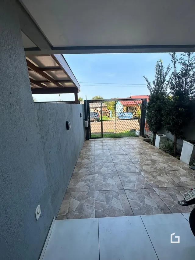 Pátio externo com piso de cerâmica e cerca no fundo da propriedade.