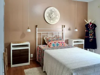 Quarto com cama de ferro branca e decoração de parede.