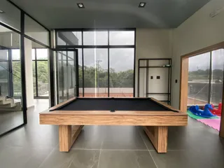 Uma sala de estar com uma mesa de bilhar de madeira no centro.