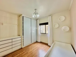 Quarto com piso de madeira e armário branco na residência.