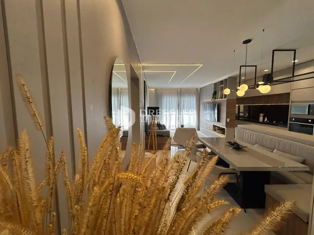 Sala de estar moderna com grandes janelas e decoração de grama dourada.