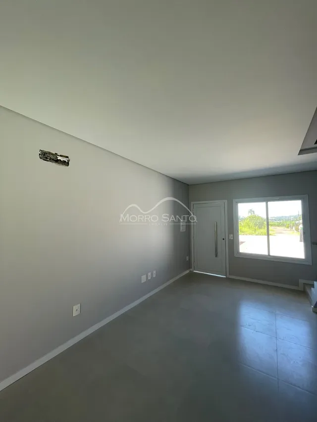 Uma sala ampla e vazia com paredes claras e piso liso.