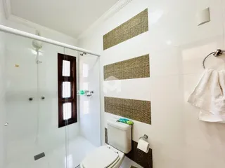 Banheiro com box de vidro e revestimento de parede.