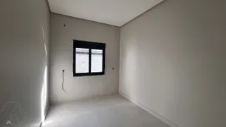 Vista de um corredor interno com paredes brancas e uma janela.