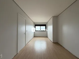 Foto de um corredor interno com piso de madeira clara e paredes brancas.