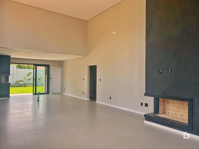 Ambiente interno de uma sala ampla com piso claro e portas de vidro que dão acesso ao exterior.