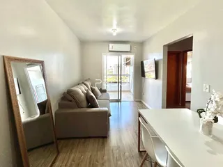 Sala de estar com sofá e piso de madeira clara.