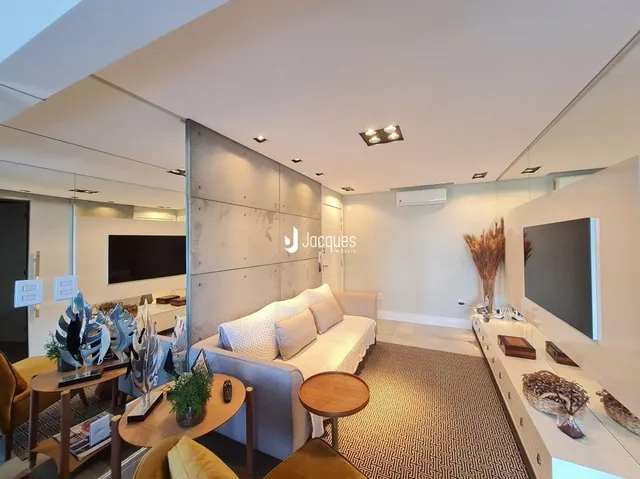 Sala de estar com sofá e televisão em um ambiente claro.
