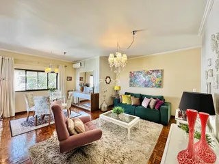 Sala de estar com piso de madeira e sofá verde em um imóvel no Brasil.