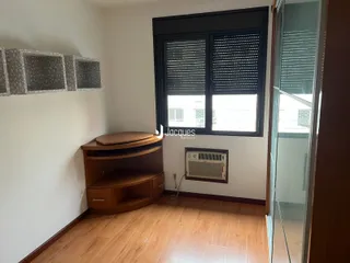 Sala de estar com piso de madeira e janela grande em um imóvel no Brasil.