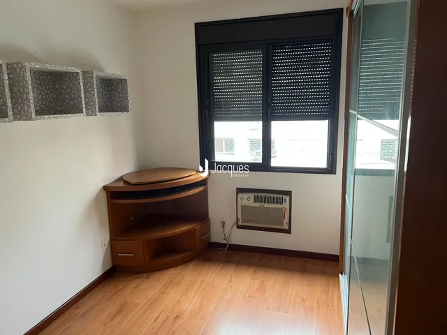 Sala de estar com piso de madeira e janela grande em um imóvel no Brasil.