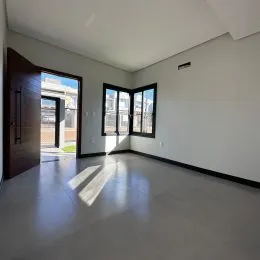 Uma sala de estar ampla com piso de concreto e grandes janelas.