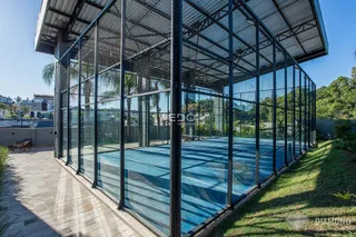 Piscina cercada por estrutura de metal e vidro em uma área externa.